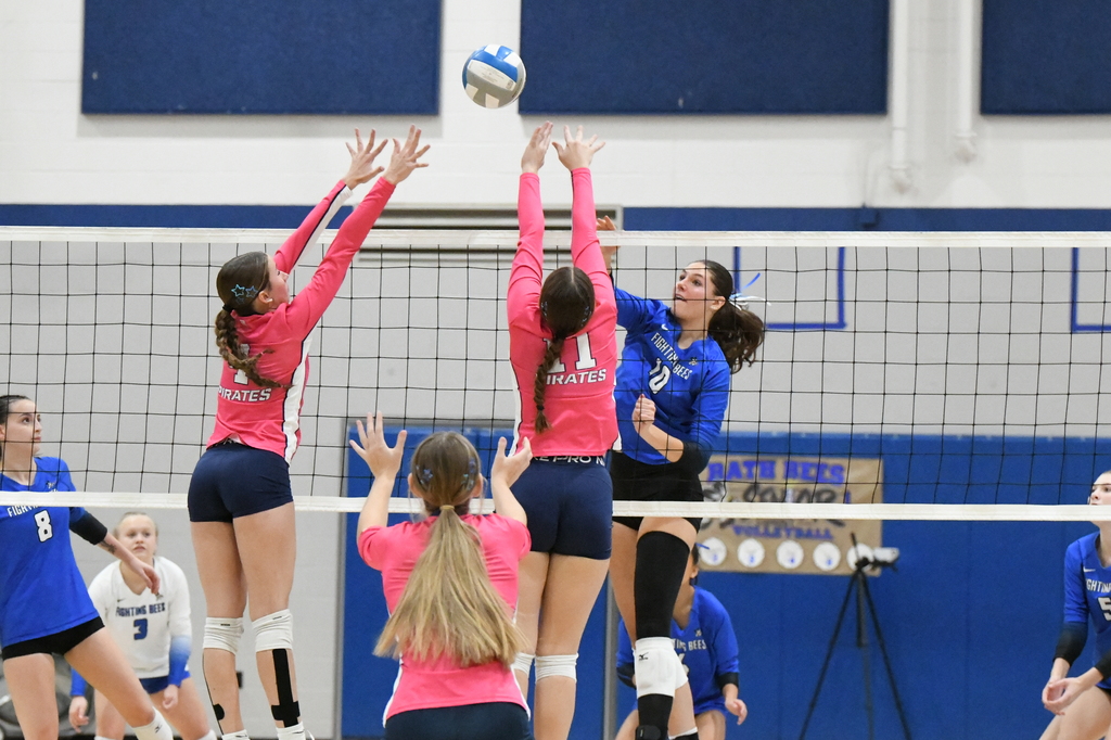 3 girls at the net jumping in the air for the ball while other players watch