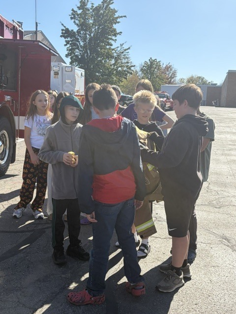 Students looking at a fire fighter's uniform