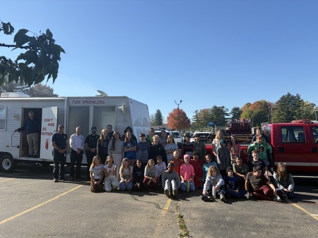 Students posing for a photo in front of fire rescue vehicles