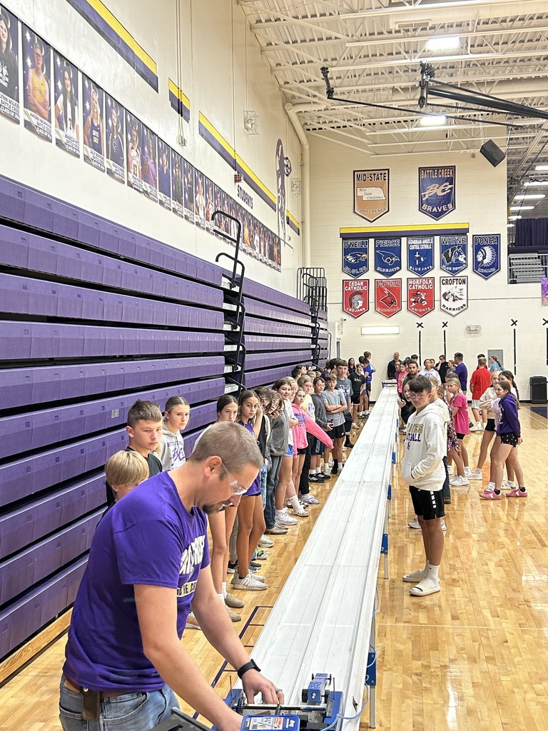 Students and staff watch as cars are set up on the race course.