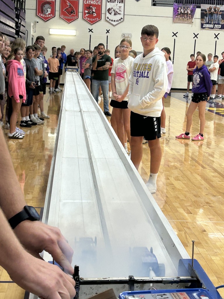 Students watch as cars race off the starting line.