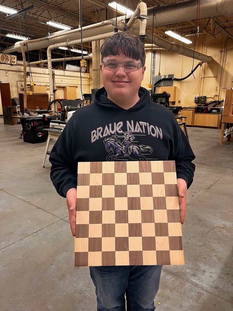 A student displays his chess board project in advanced woodworking.