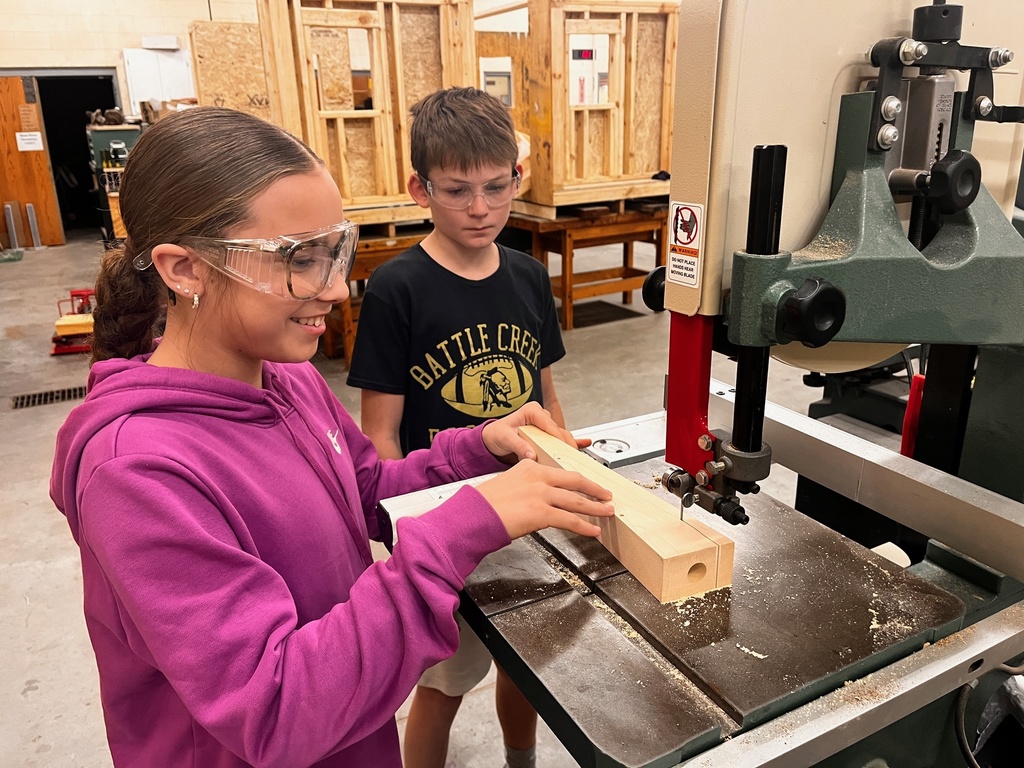 Students cut a wood car body out using the band saw.