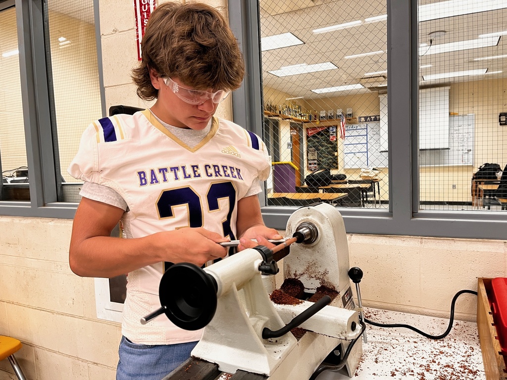 A student shapes a pen blank on the lathe.