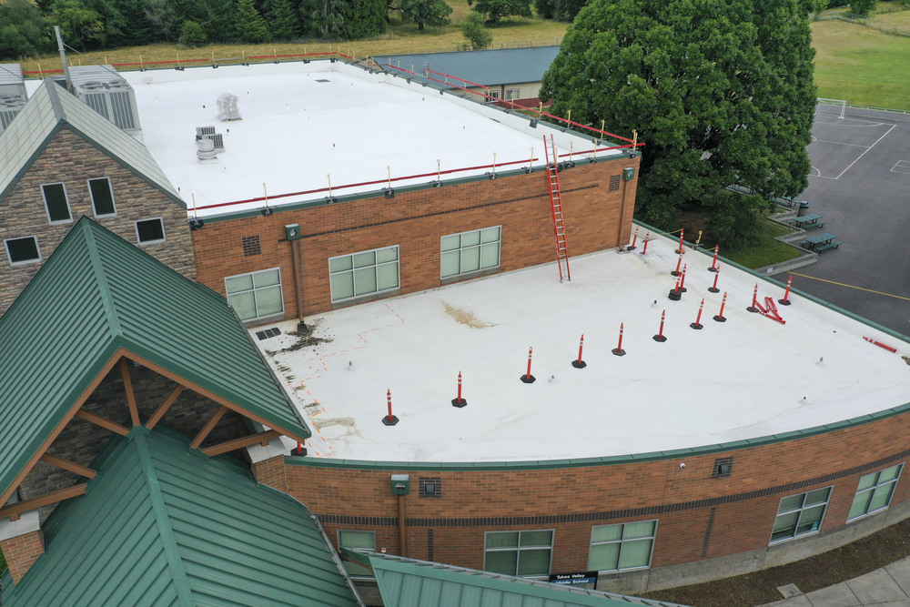 A school building seen from above with orange cones and barriers set up