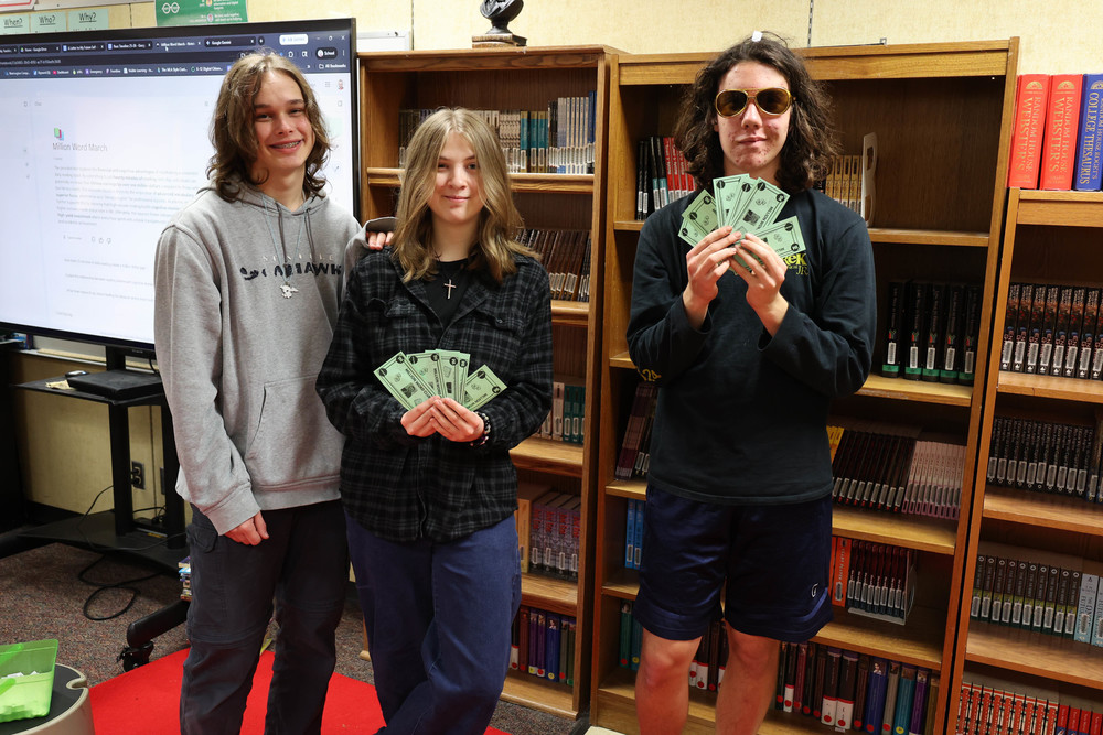 Students display the pretend money they earned by reading