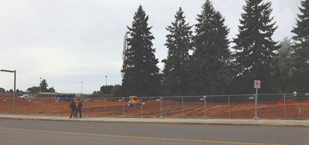 Two people walk past the construction site