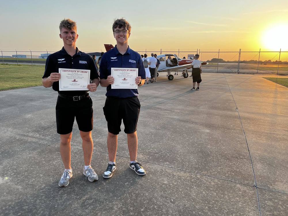 Two students display their certificates for a private pilot airplane single engine land
