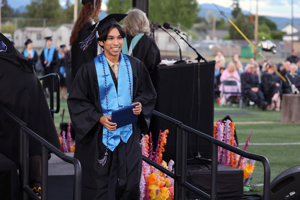 A grad smiles after receiving a diploma