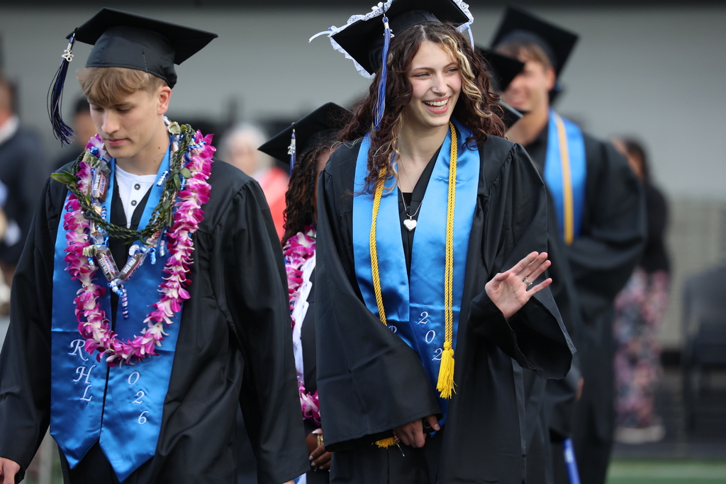 A grad waves at the crowd