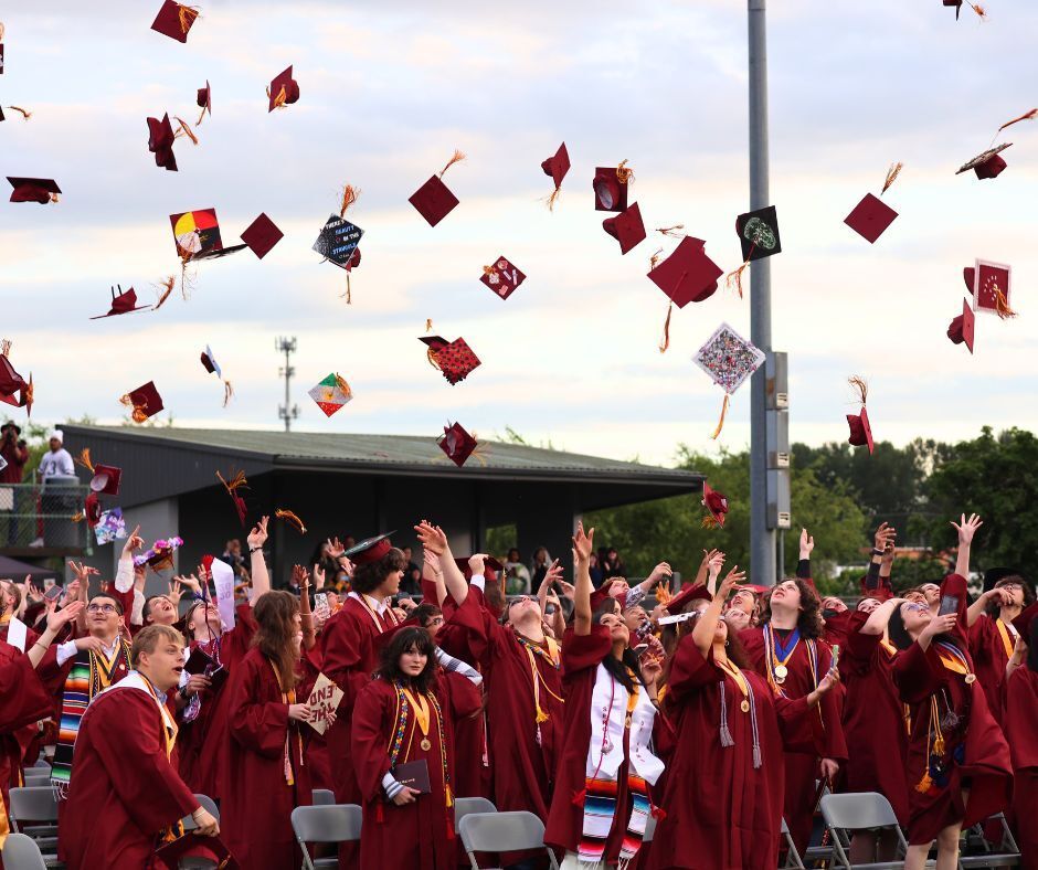 Graduates toss their caps into the air.