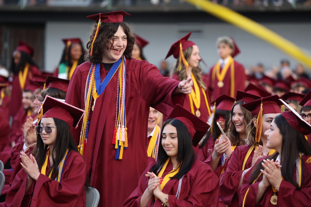 A grad smiles and points during the ceremony.