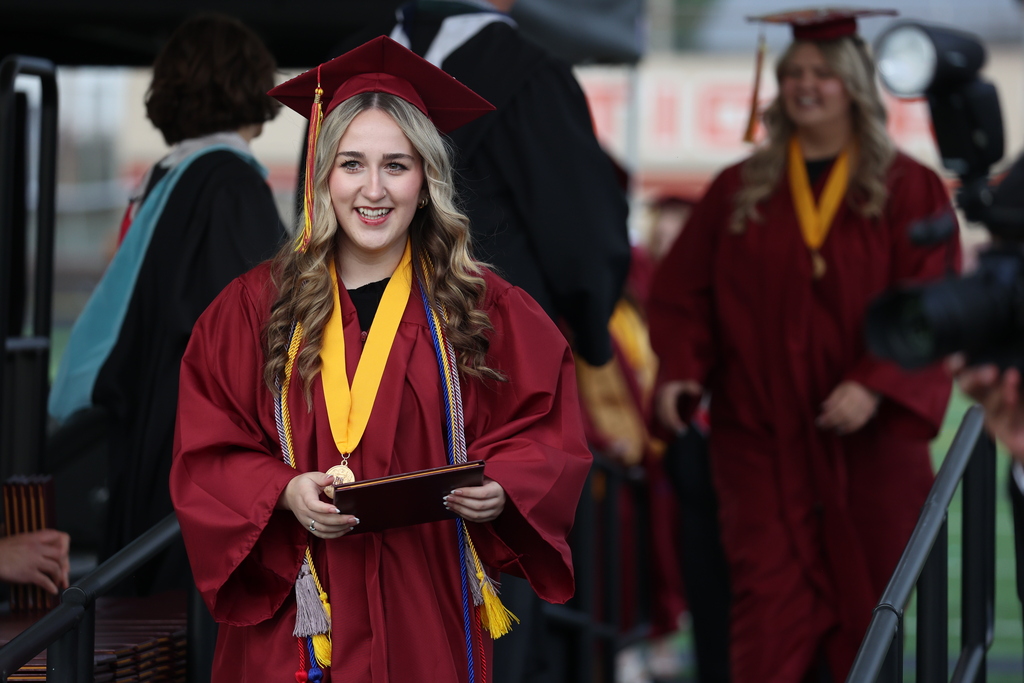 A grad smiles after receiving a diploma.