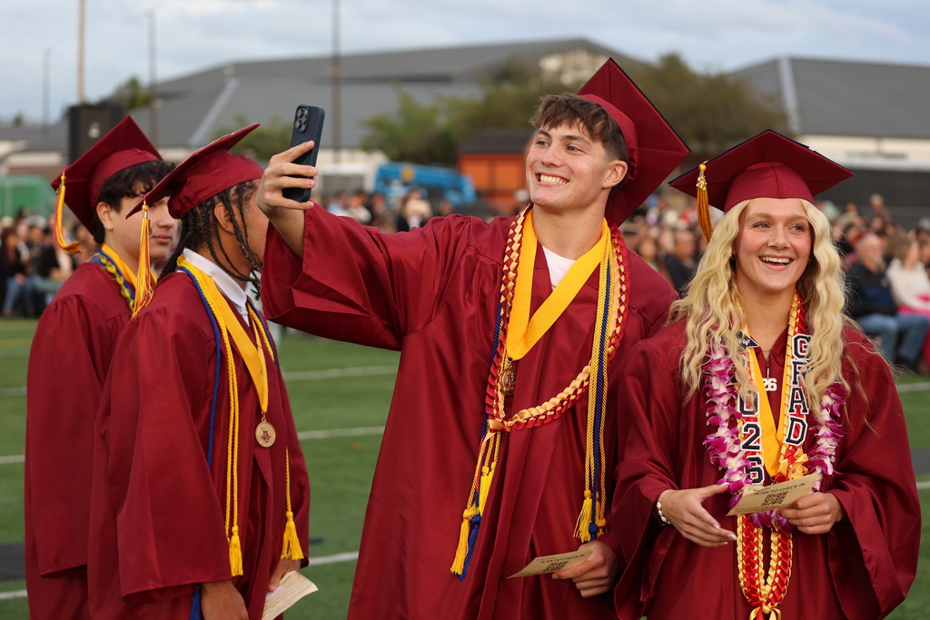 Grads take selfies while waiting to receive their diploma.