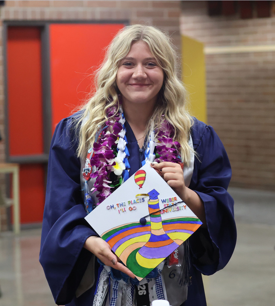 A proud young woman shows off her cap which says "oh the places you will go"