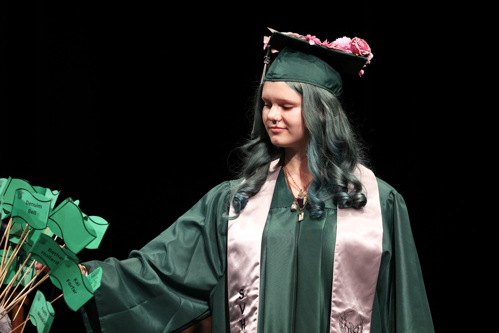 A graduate plants a flag during commencement