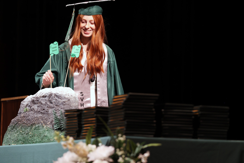 A graduate plants a flag at the Summit View commencement ceremony.