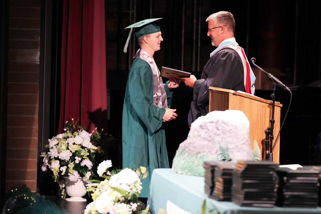 A Summit View High School grad accepts an award from the principal.
