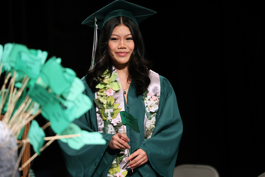 A graduate smiles while preparing to plant a flag during commencement