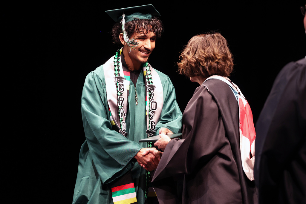 A graduate shakes the superintendent's hand as he accepts his diploma.