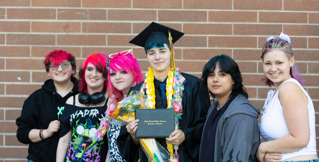 A young gradate poses with their friends with colorful hair
