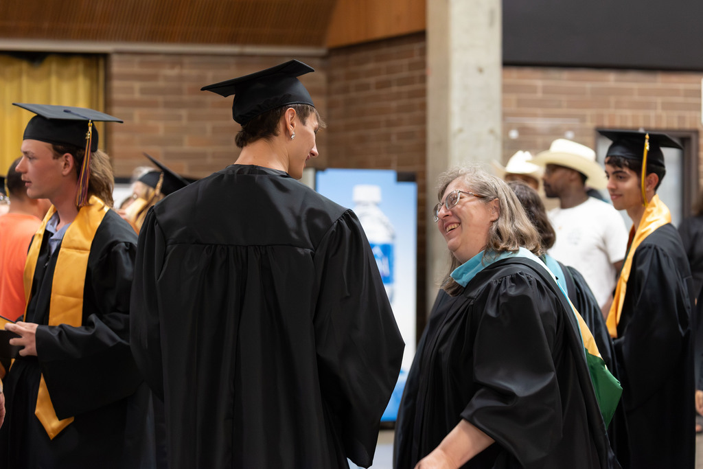 A teacher looks proudly smiling at her student who just graduated
