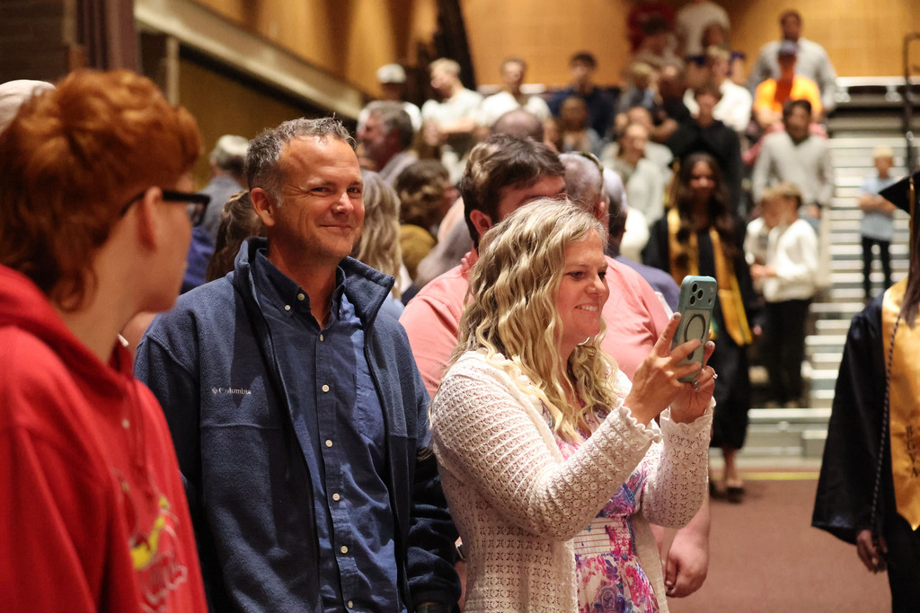 A pround mom and dad snap a photo of their graduate inside the auditorium