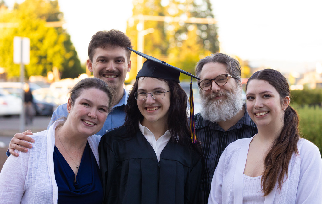 A family smiles for the camera with their proud graduate