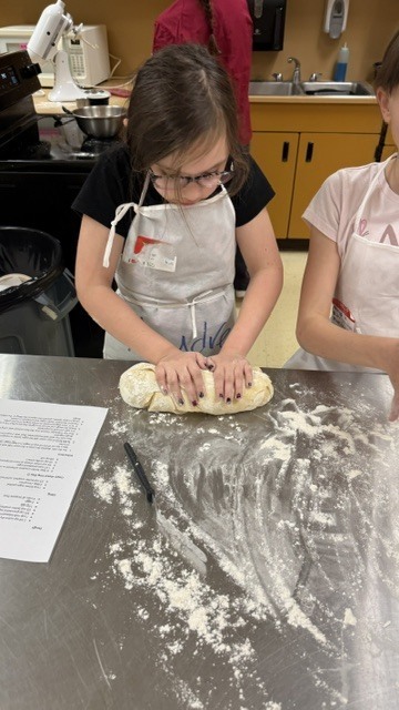 A student rolls out a loaf of bread