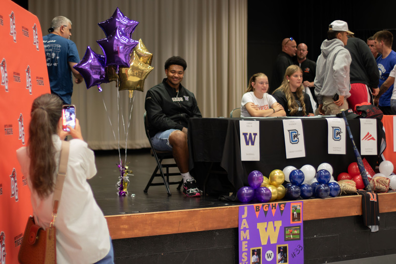 a parent takes a photo of a smiling teenager on state