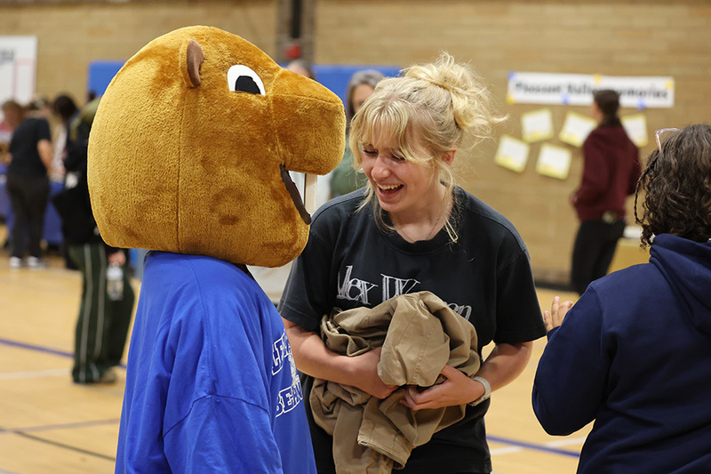 A person smiles at the primary school's mascot