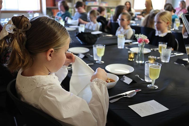 a young girl places her napkin on her lap