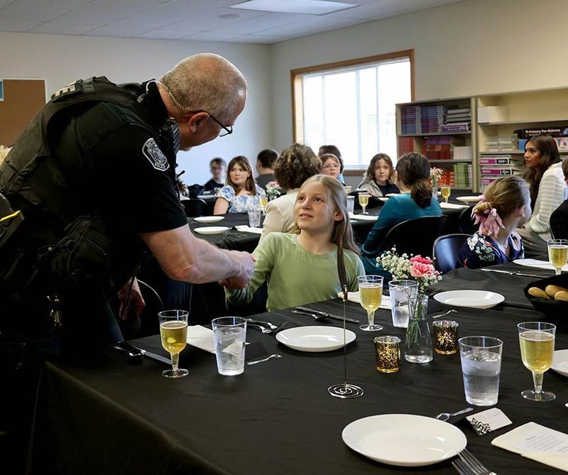 a young student shakes the hand of a police officer