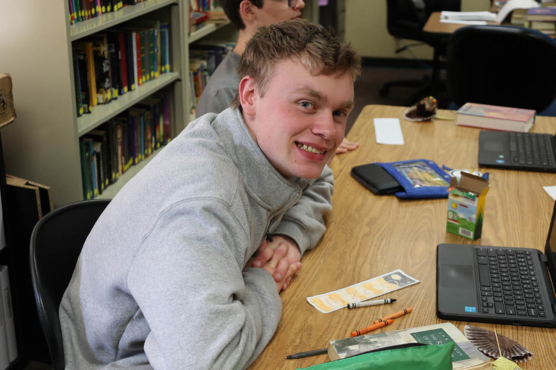 A student smiles at the camera after creating a bookmark