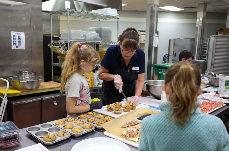 A Chartwells staff member helps a student slice a muffin