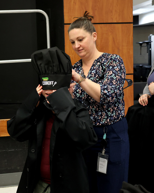 A student tries on a chef's jacket