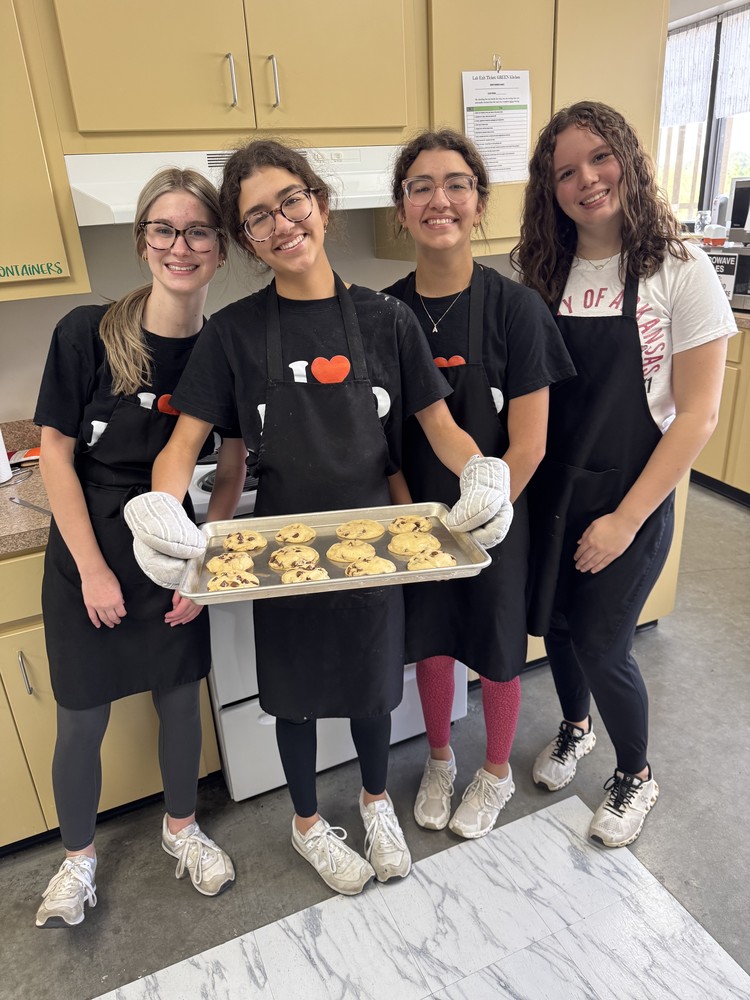 Four girls holding a pan with cookies.
