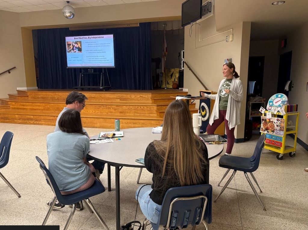 A staff member speaks to a small group of parents about building independence and daily routines for students with IEPs.