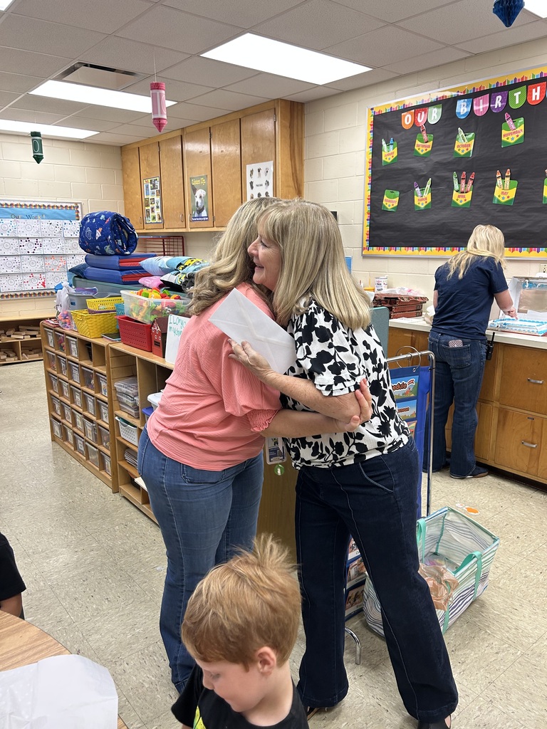 two women hugging with check for the school