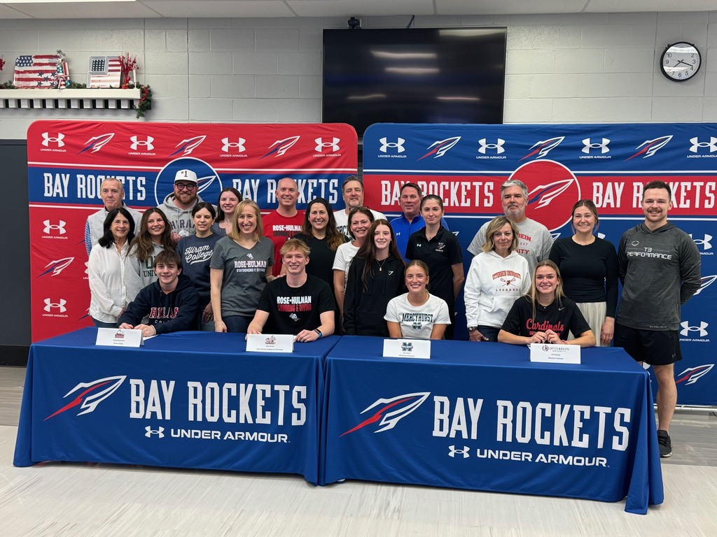 Signing day for four Bay High School student-athletes continuing their athletic careers at their respective universities. Students and families with their coaches in a group photo.
