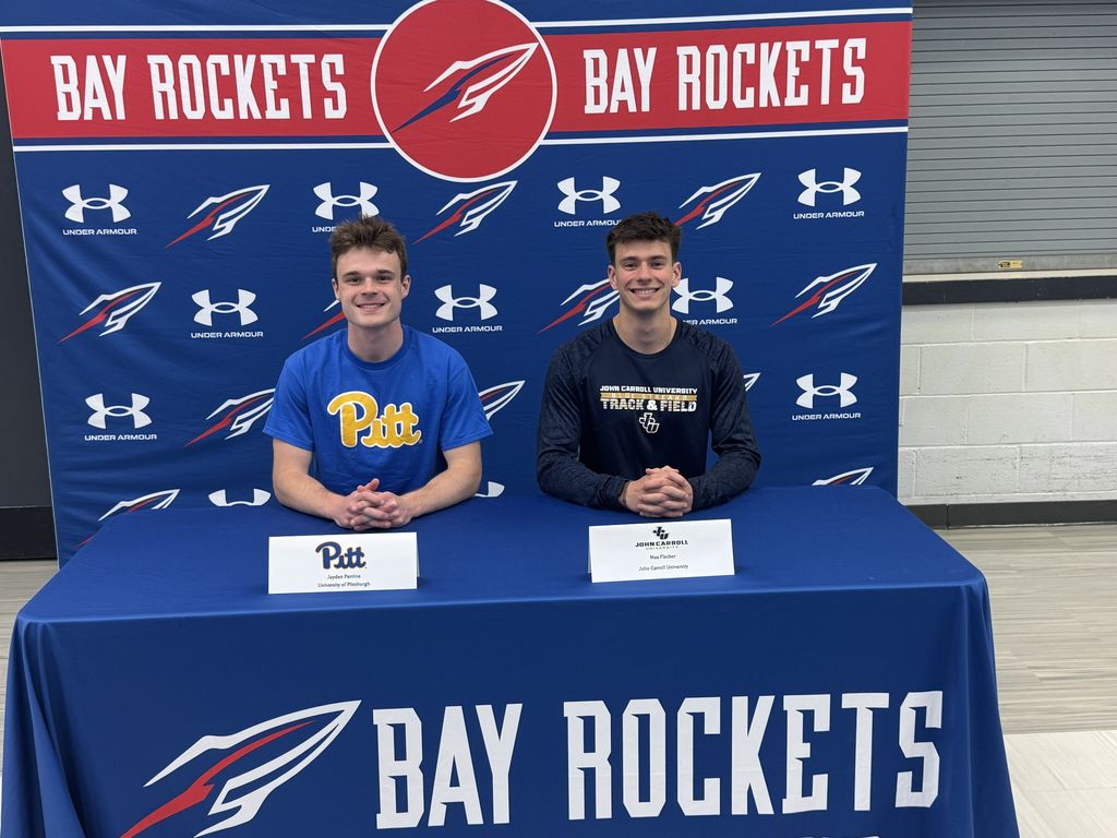 Two Bay High School student-athletes sitting at a table ready to sign their NLIs for their college careers.
