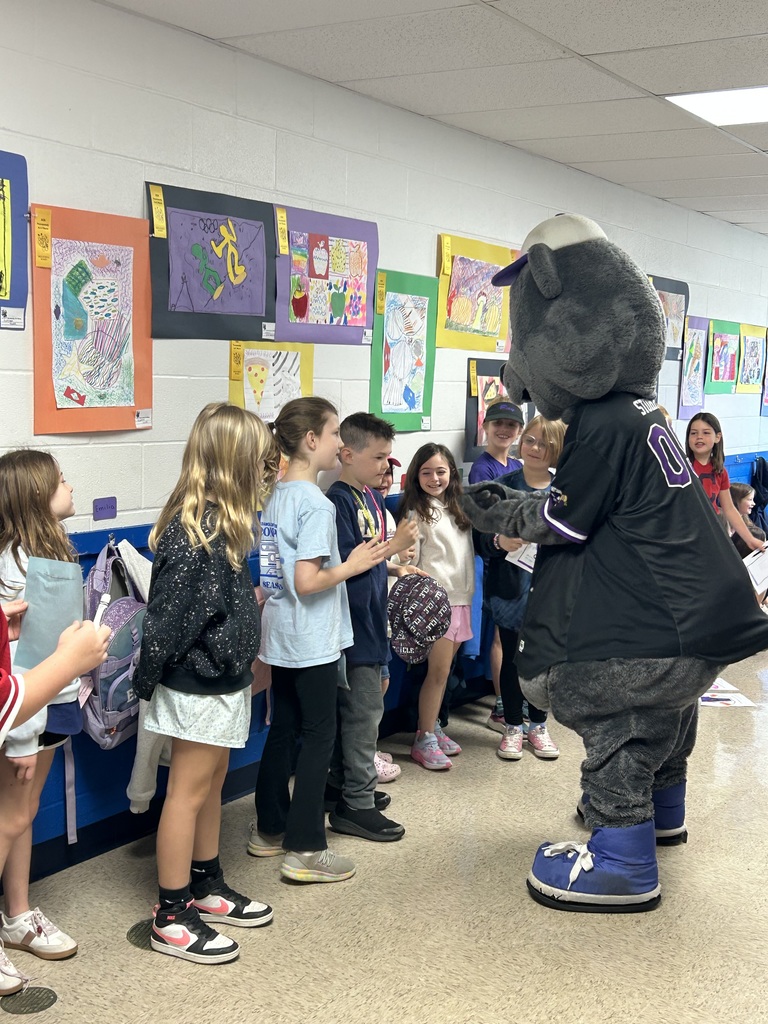 Crushers baseball mascot Stomper is shown with students  in the hallway of Normandy School in Bay Village.