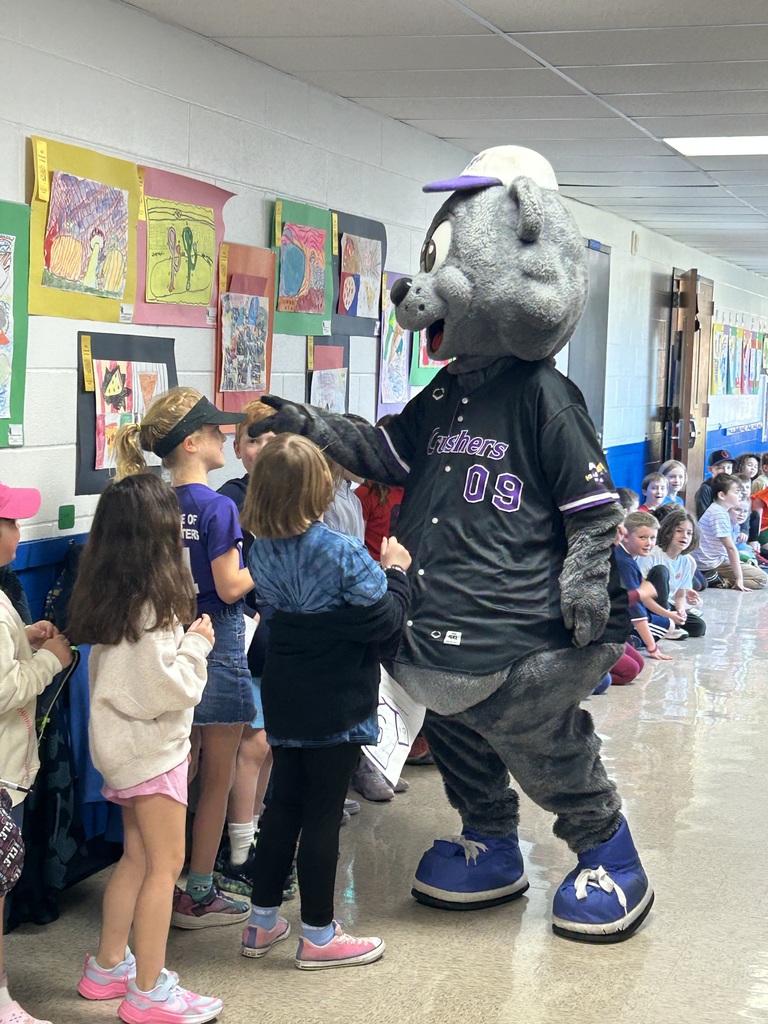 Crushers baseball mascot Stomper is shown with students  in the hallway of Normandy School in Bay Village.