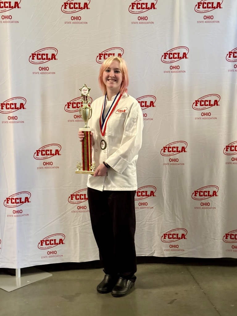 A Bay High School Senior culinary student holding a large trophy for winning the state championship in baking and pastry.