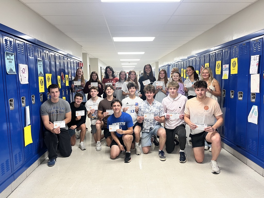 Seniors in Calculus class in the hallway by blue lockers holding up certificates.