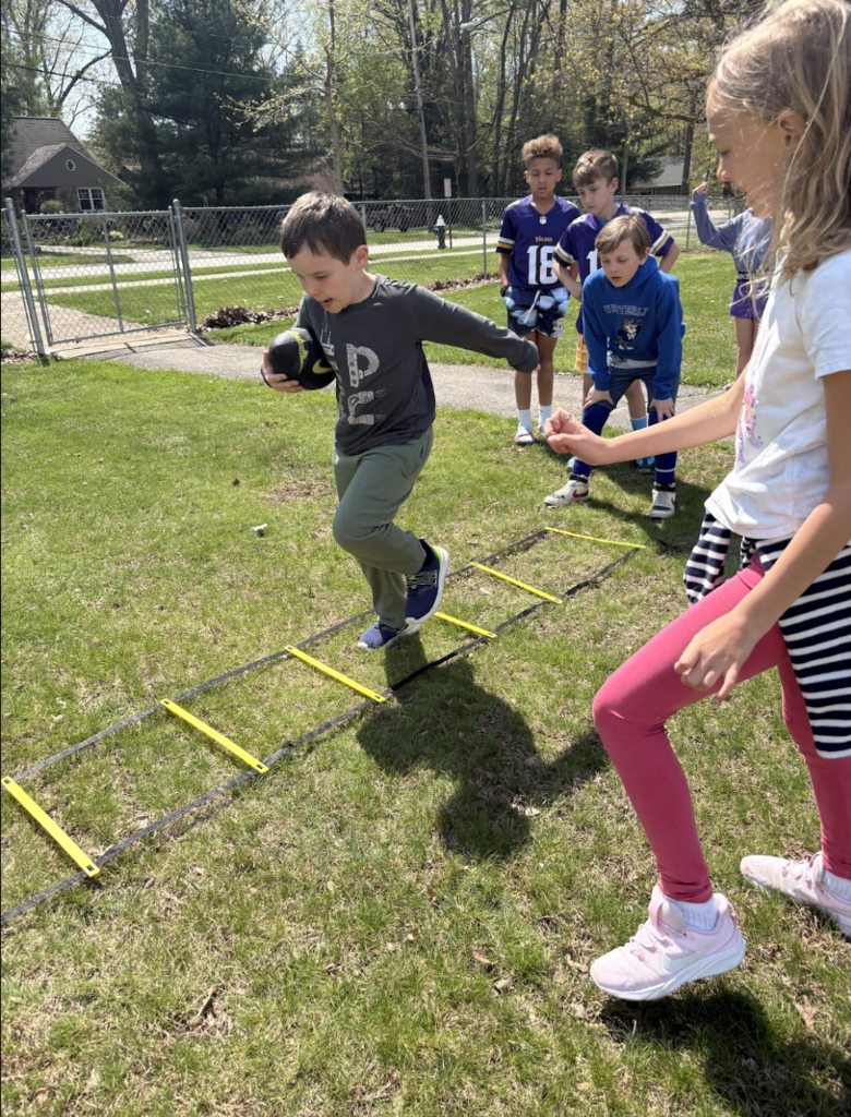 A Glenview student runs with a football during the ground ladder drill.