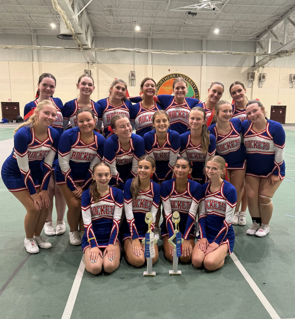 A photo of the Bay High 2026-27 Cheer Squad with trophies in front of them.