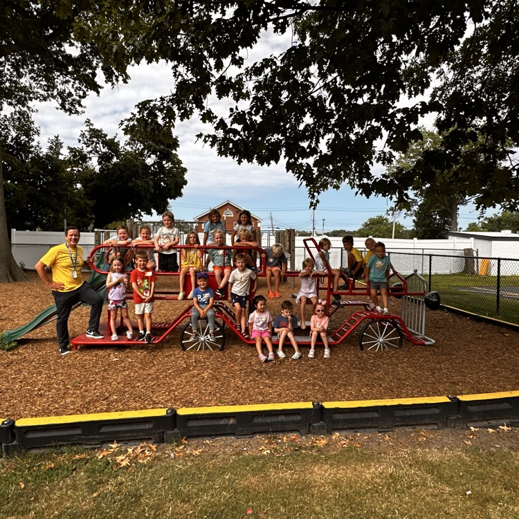 The class of 2039 play date. Students are perched on a playground fire engine.