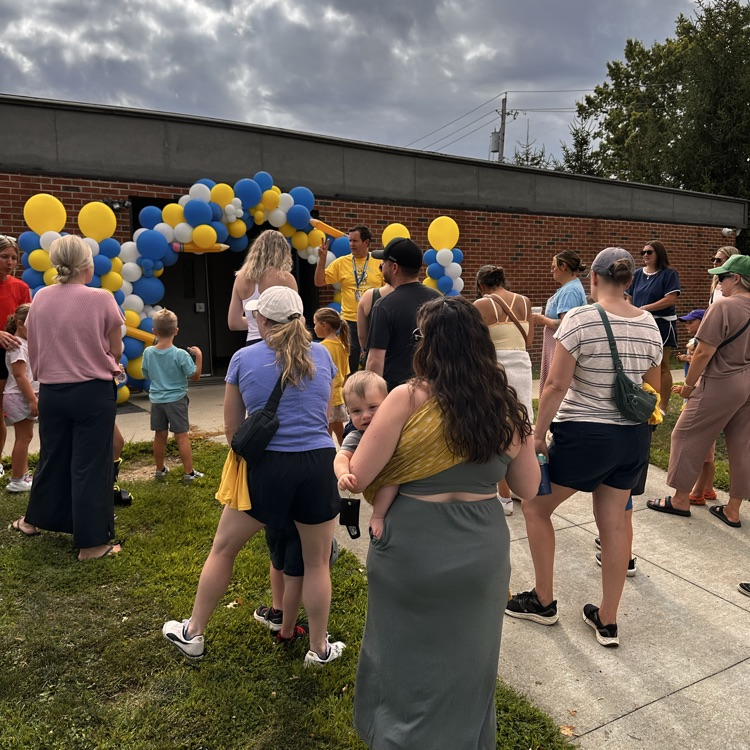 two moms are taking photos of their students in front of a balloon arch