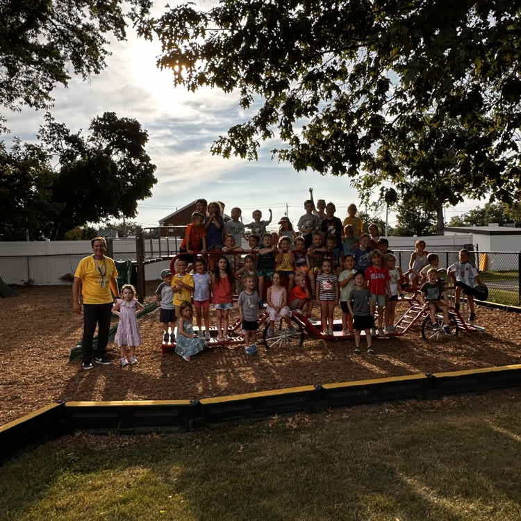 kindergarten students pose for a photo on the playground with their principal